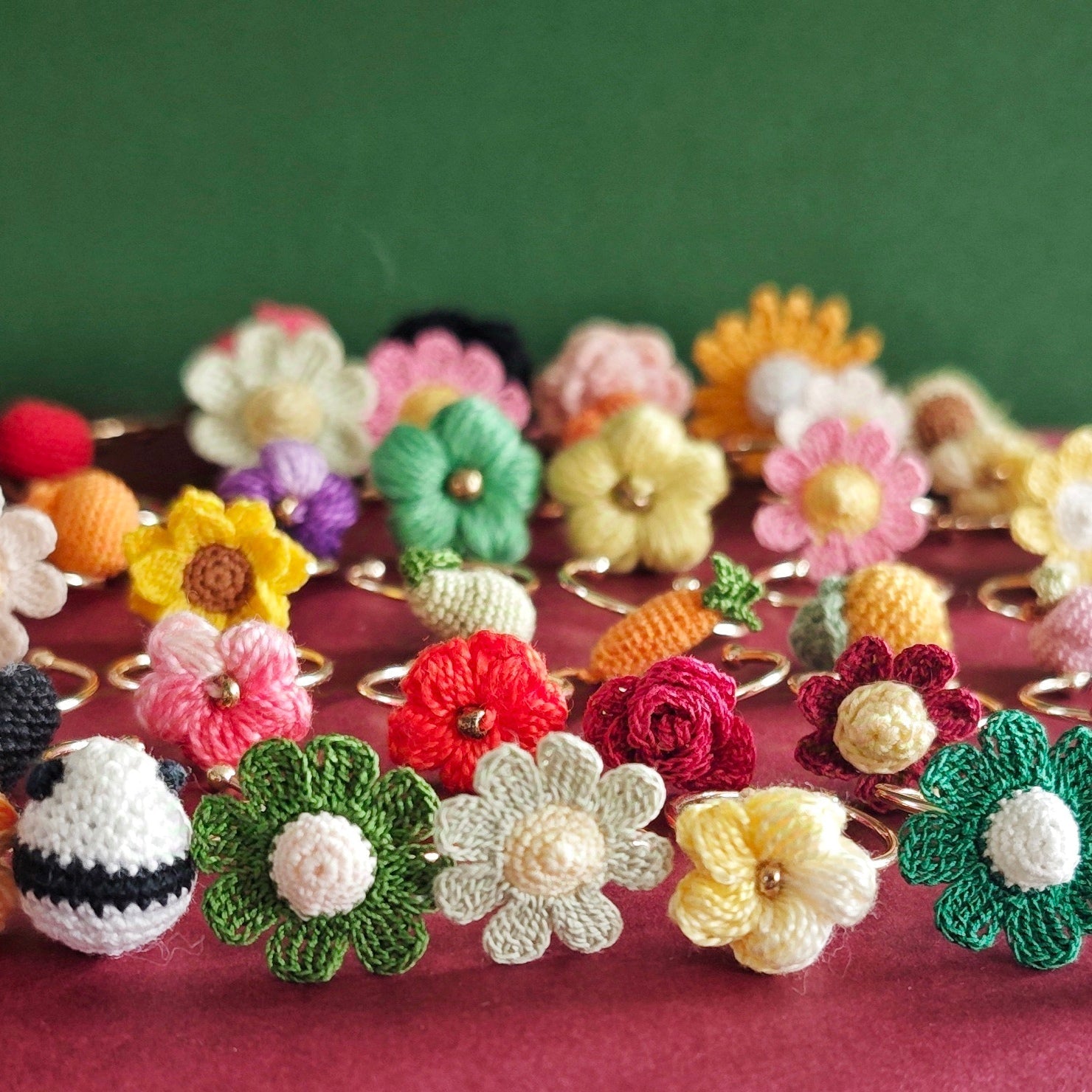 Présentation de plusieurs bagues en crochet faites à la main, avec des motifs de fleurs, de fruits, de petits animaux et de cœurs. Chaque bague est colorée et unique, adaptée à différents styles et humeurs.