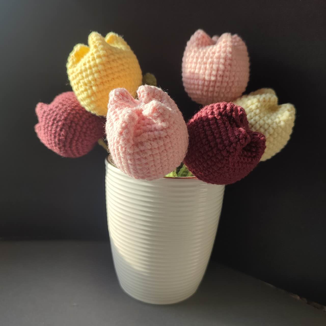 Six tulipes en crochet avec différentes couleurs et feuilles vertes, présentées dans un kit.